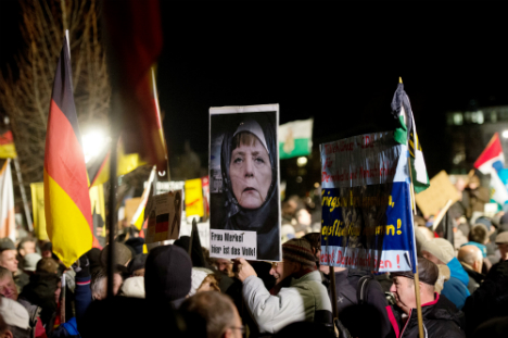 A Dresden PEGIDA marcher holds a picture of Merkel wearing a head scarf. Photo: DPA